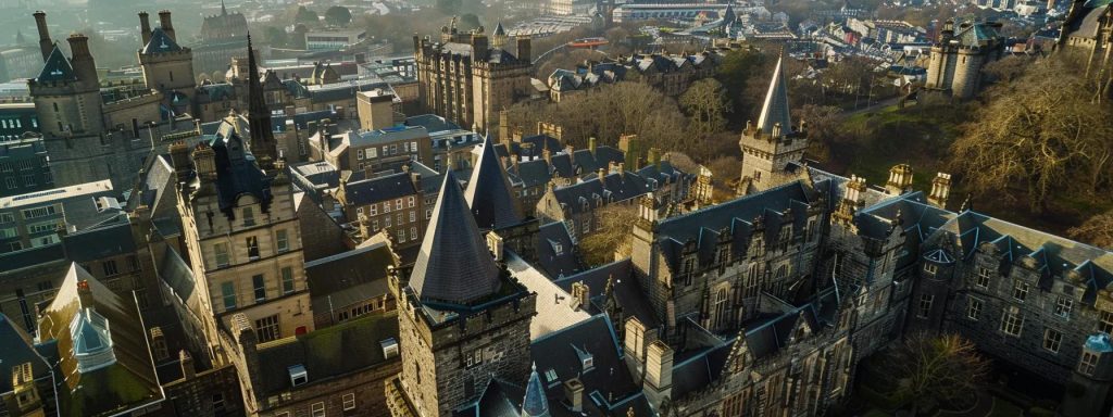 a majestic view of cardiff castle, showcasing its steep gables and ornate turrets against a dramatic urban backdrop, highlighting the intricate stone carvings and gothic elements that embody the city's rich architectural heritage.